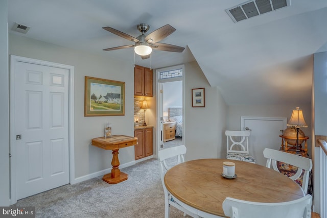 dining room with light colored carpet, ceiling fan, and baseboards