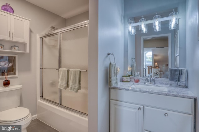 bathroom featuring toilet, combined bath / shower with glass door, vanity, and tile patterned floors