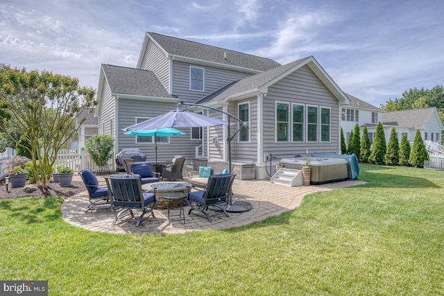 rear view of house with a hot tub, a patio, an outdoor fire pit, and a shingled roof