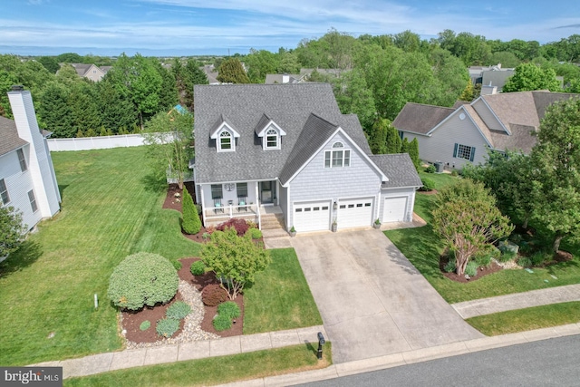 view of front of property with a porch, driveway, a front lawn, and an attached garage