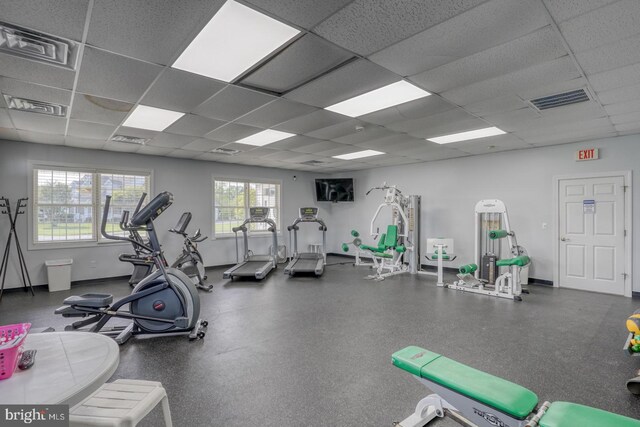 gym with a drop ceiling and baseboards
