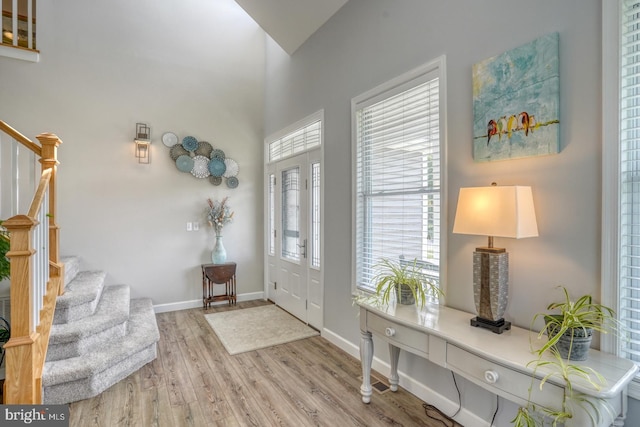 foyer with stairway, wood finished floors, and baseboards
