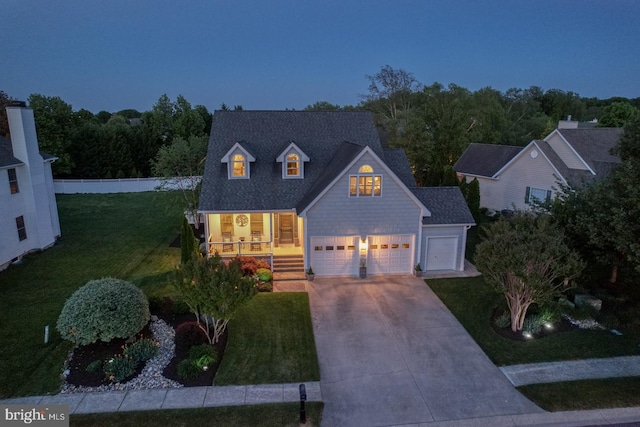 view of front of property featuring concrete driveway, a front lawn, an attached garage, and a porch