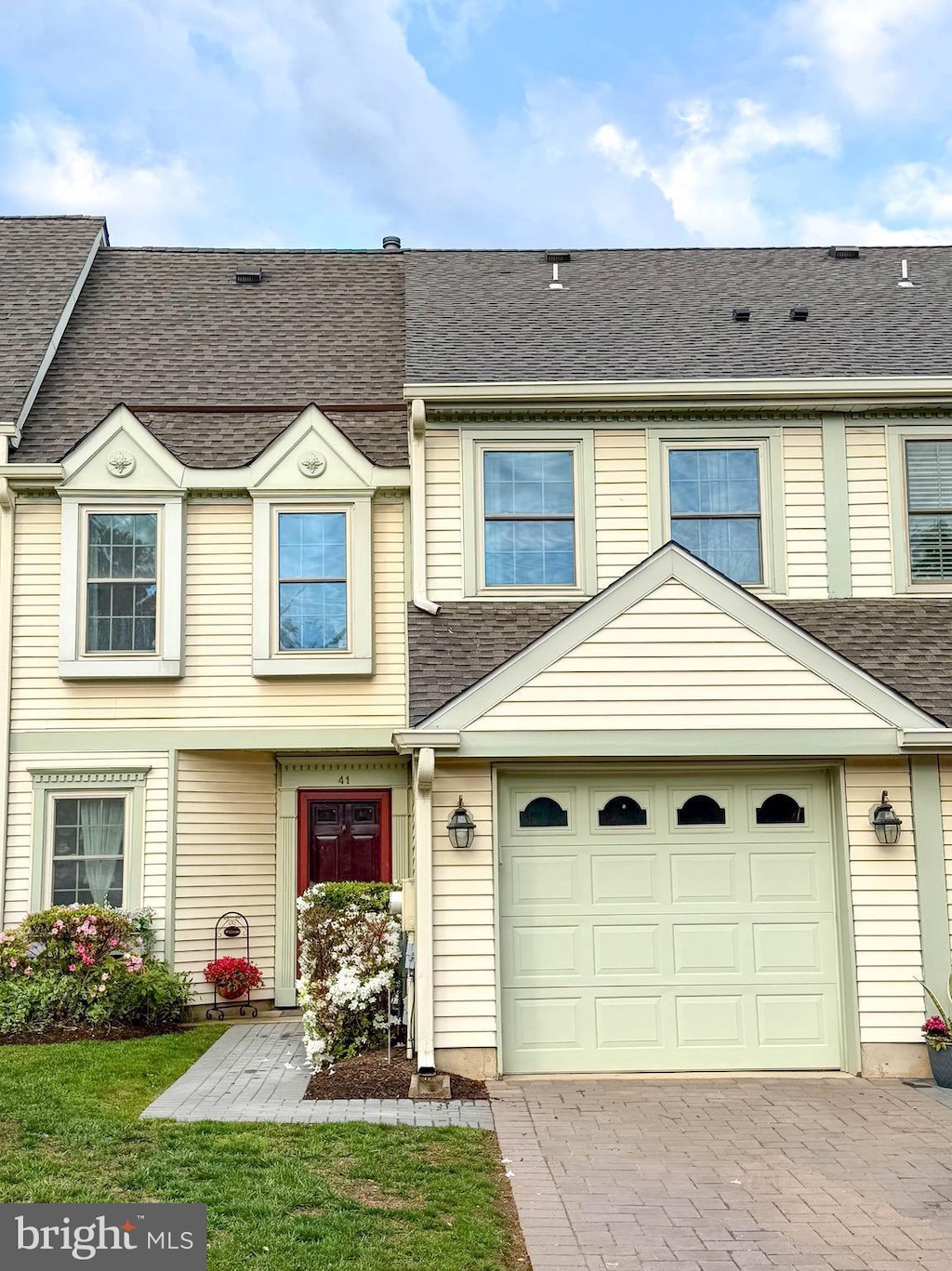 townhome / multi-family property featuring decorative driveway, a garage, and roof with shingles