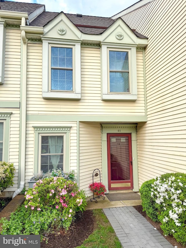 doorway to property with a shingled roof