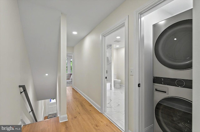 laundry room featuring stacked washer / drying machine, baseboards, light wood-style flooring, and recessed lighting