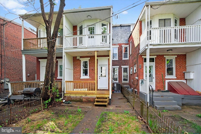 townhome / multi-family property featuring a balcony, brick siding, central AC, and fence