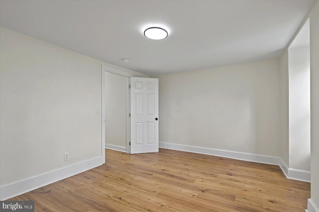 spare room featuring baseboards and light wood-style floors