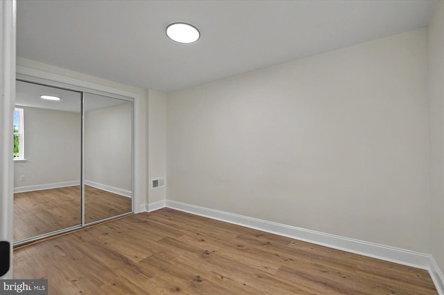 unfurnished bedroom featuring baseboards, wood finished floors, and a closet