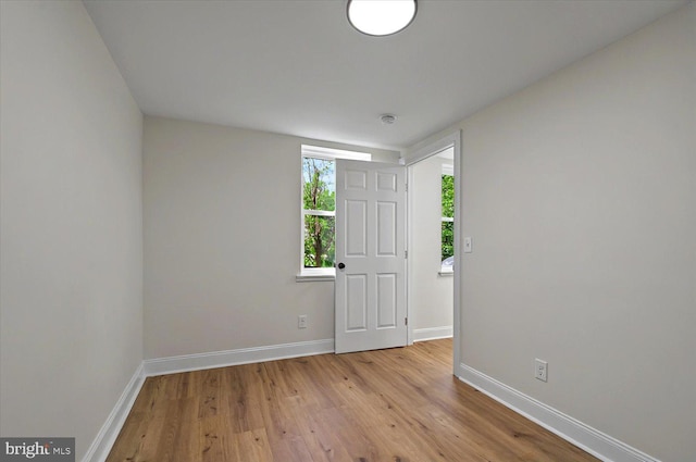 spare room featuring baseboards and light wood finished floors