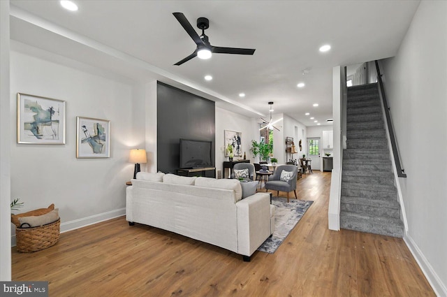 living room with stairs, wood finished floors, a ceiling fan, baseboards, and recessed lighting