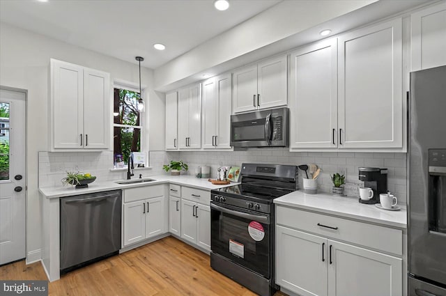 kitchen featuring stainless steel appliances, a sink, healthy amount of natural light, light wood-type flooring, and recessed lighting