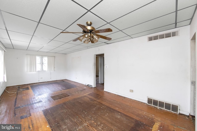 spare room featuring wood-type flooring, a ceiling fan, and a paneled ceiling