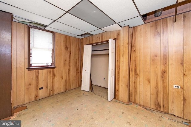 unfurnished bedroom with wood walls and a paneled ceiling