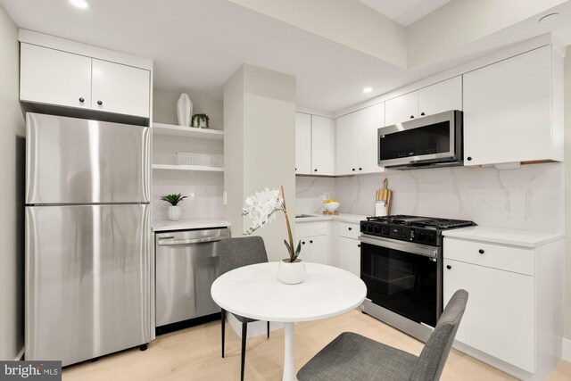 kitchen with appliances with stainless steel finishes, open shelves, light countertops, recessed lighting, and white cabinets