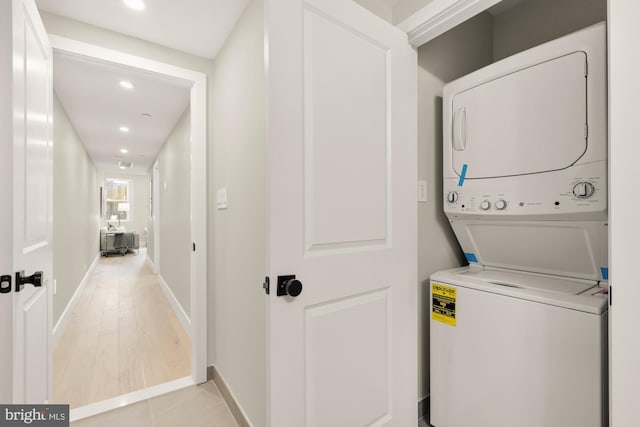 laundry area with estacked washer and dryer, recessed lighting, and baseboards
