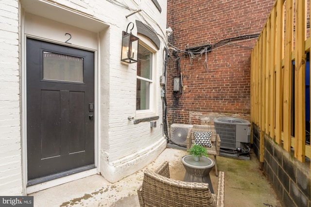 property entrance featuring cooling unit and brick siding