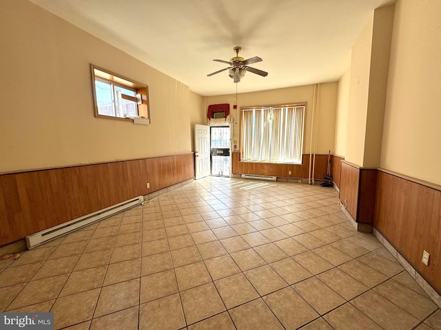 1331 Mifflin St, Philadelphia, PA 19148 - empty room with a baseboard heating unit, a wainscoted wall, wooden walls, ceiling fan, and light tile patterned floors