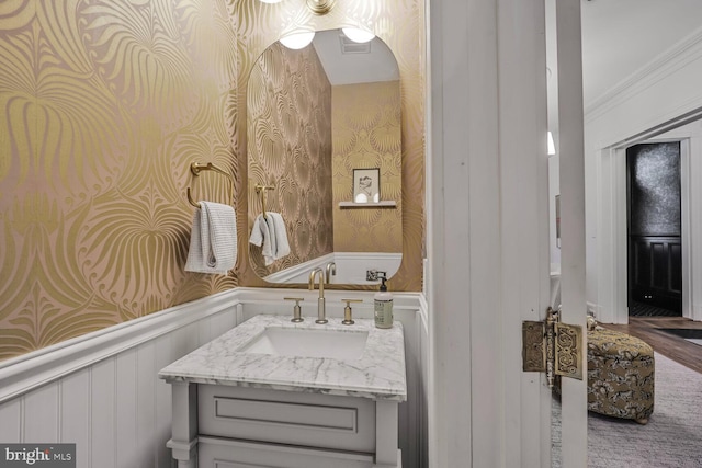 bathroom featuring wallpapered walls, wainscoting, vanity, and wood finished floors