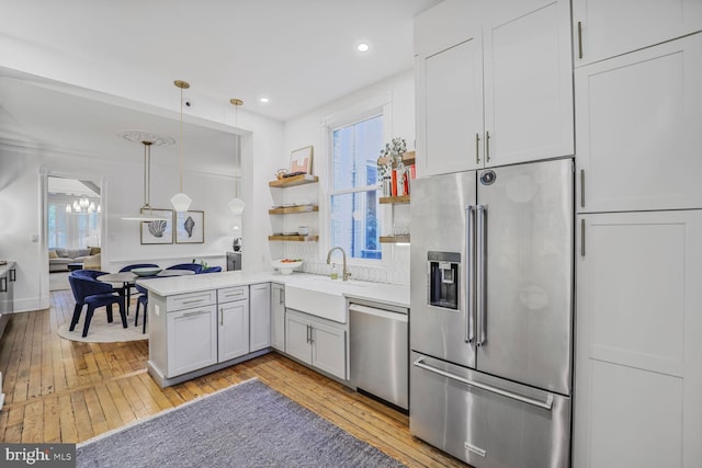kitchen with appliances with stainless steel finishes, a sink, light wood-type flooring, plenty of natural light, and recessed lighting