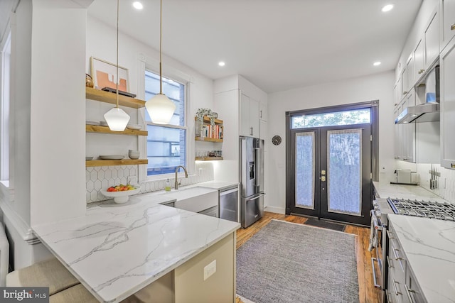kitchen with open shelves, premium appliances, a sink, backsplash, and light wood finished floors