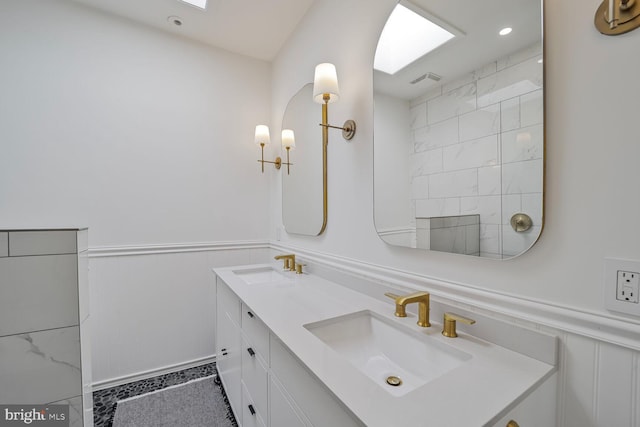 full bath with a wainscoted wall, double vanity, recessed lighting, and a decorative wall