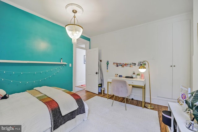 bedroom featuring wood finished floors, crown molding, and baseboards