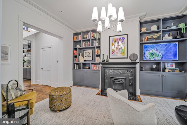 living area featuring ornamental molding, a chandelier, built in shelves, wood finished floors, and a high end fireplace