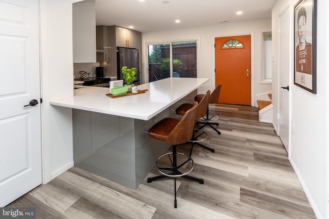23 Eden Roc, New Hope, PA 18938 - kitchen with freestanding refrigerator, light wood-style floors, a kitchen bar, light countertops, and a peninsula