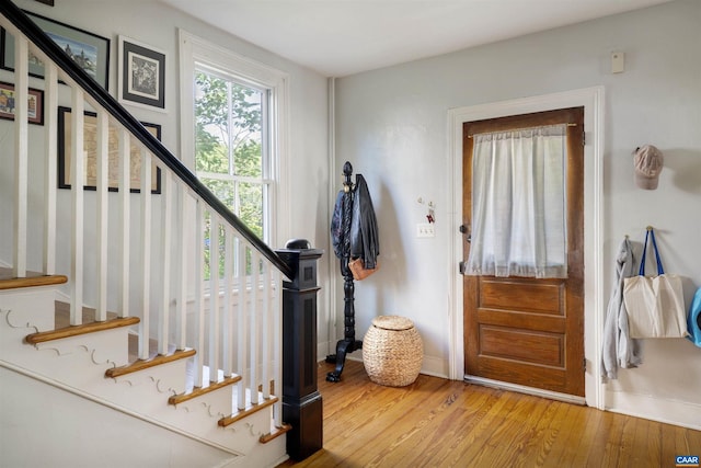 foyer featuring baseboards, wood finished floors, and stairs