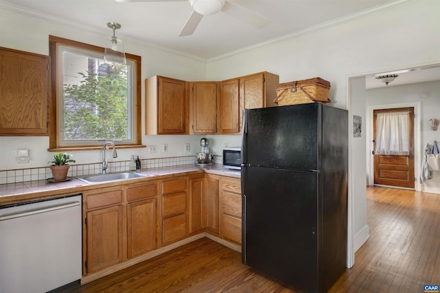 kitchen with freestanding refrigerator, dishwasher, a sink, tile counters, and stainless steel microwave
