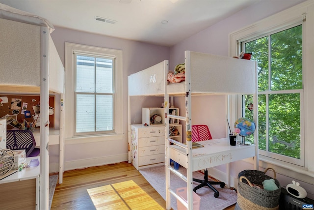 bedroom featuring multiple windows, wood finished floors, and baseboards