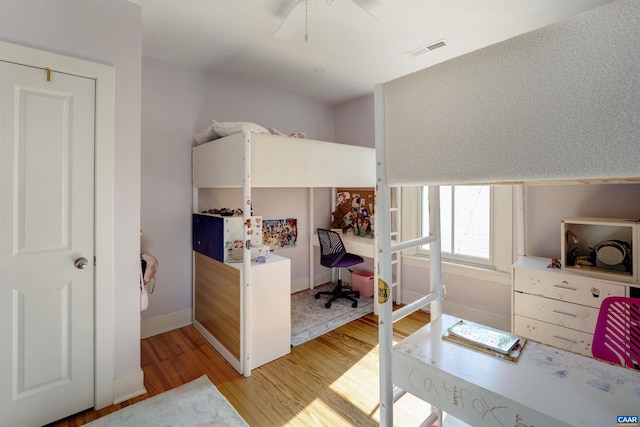 bedroom with light wood-style floors, baseboards, a ceiling fan, and a desk