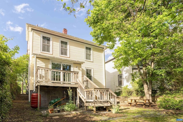 rear view of house featuring stairway, a wooden deck, and a chimney