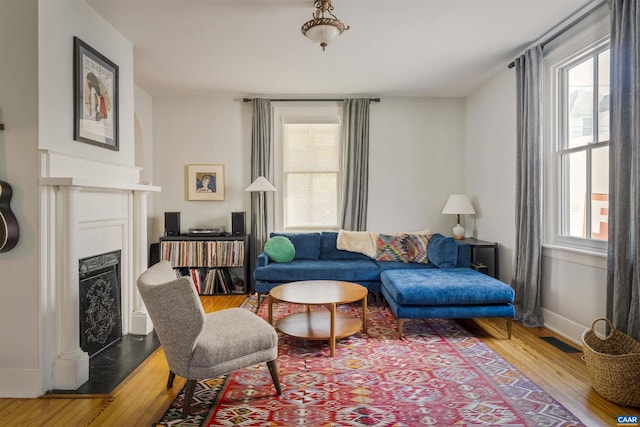 living area featuring wood finished floors, a fireplace with raised hearth, and baseboards