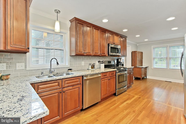 kitchen featuring appliances with stainless steel finishes, a sink, ornamental molding, brown cabinetry, and backsplash