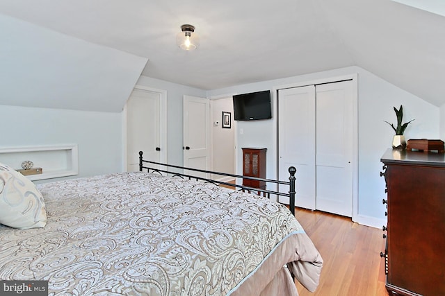 bedroom featuring light wood-style flooring, lofted ceiling, and a closet