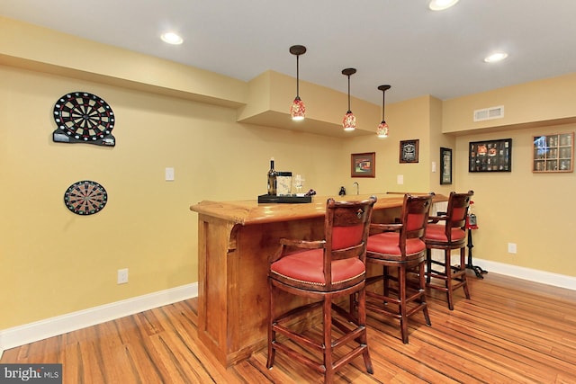 indoor dry bar featuring baseboards, light wood-style floors, recessed lighting, and hanging light fixtures