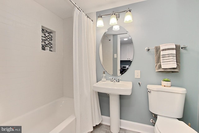 full bath featuring toilet, baseboards, shower / tub combo with curtain, and a sink