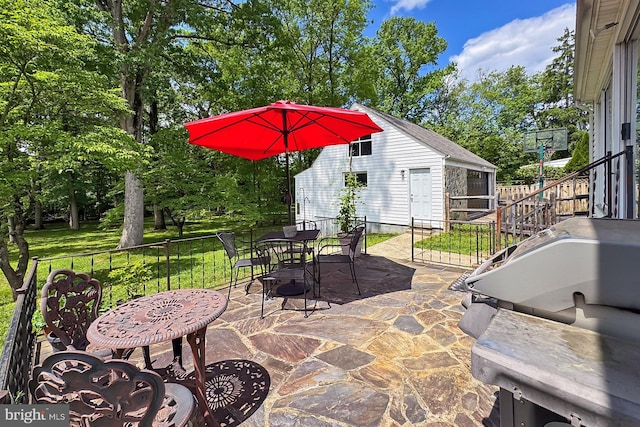 view of patio featuring outdoor dining space, view of scattered trees, and an outbuilding