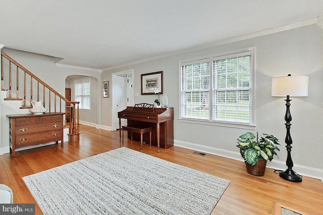 entryway featuring arched walkways, wood finished floors, ornamental molding, stairway, and baseboards