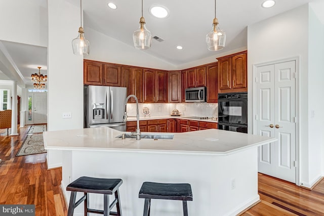 16453 Sparkling Brook Loop, Dumfries, VA 22025 - kitchen with black appliances, light wood finished floors, backsplash, a chandelier, and an island with sink
