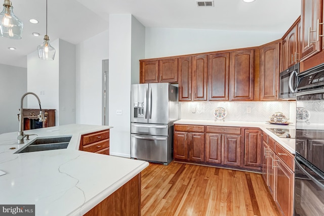 16453 Sparkling Brook Loop, Dumfries, VA 22025 - kitchen featuring appliances with stainless steel finishes, light wood finished floors, lofted ceiling, decorative light fixtures, and decorative backsplash