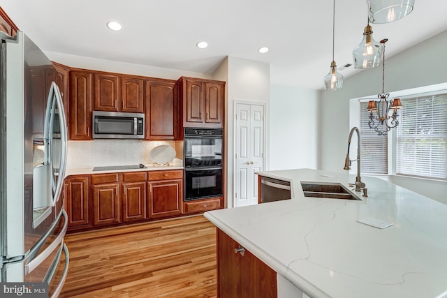 16453 Sparkling Brook Loop, Dumfries, VA 22025 - kitchen with black appliances, light wood-style floors, decorative light fixtures, tasteful backsplash, and recessed lighting