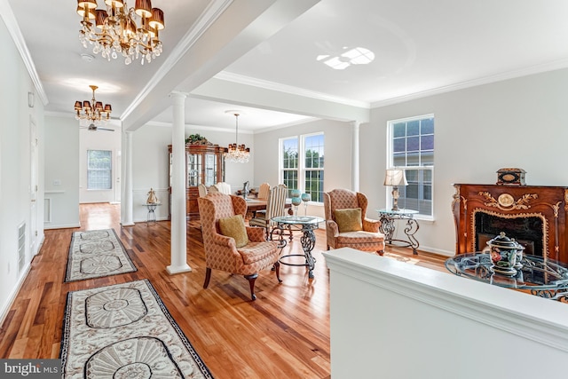 16453 Sparkling Brook Loop, Dumfries, VA 22025 - living room featuring a chandelier, ornate columns, light wood finished floors, ornamental molding, and a fireplace