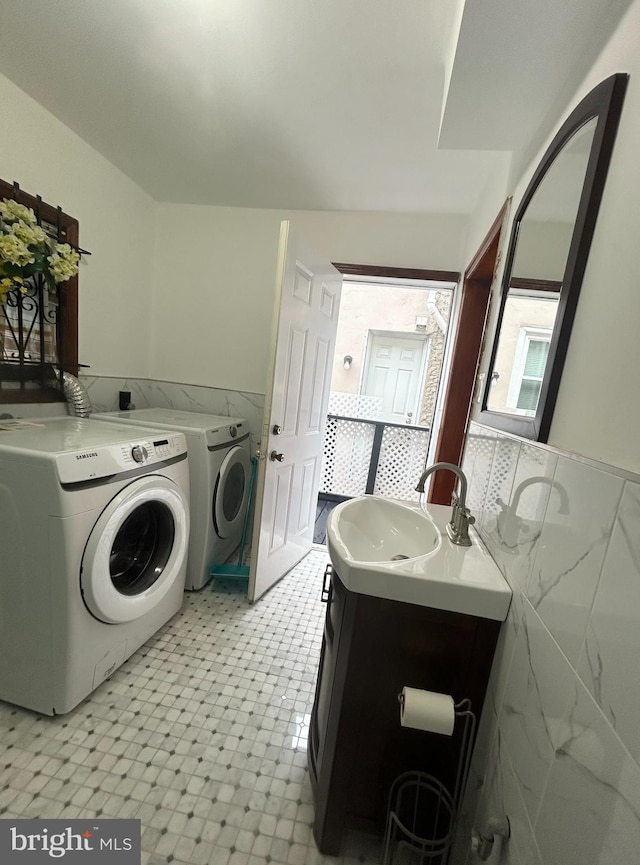 washroom featuring washer and clothes dryer, tile walls, light floors, and wainscoting