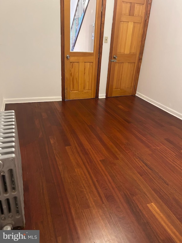 foyer featuring radiator, wood finished floors, and baseboards