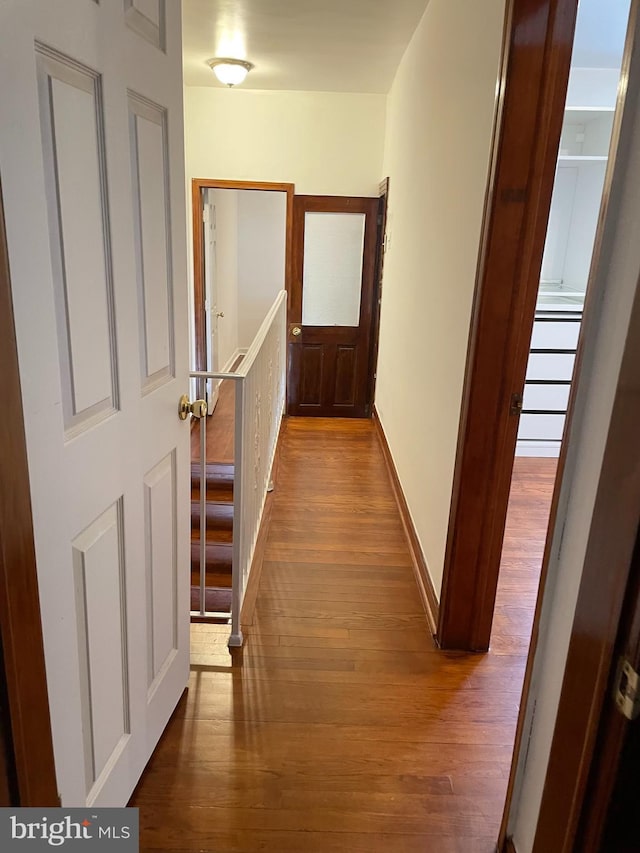 hall with hardwood / wood-style floors, an upstairs landing, and baseboards