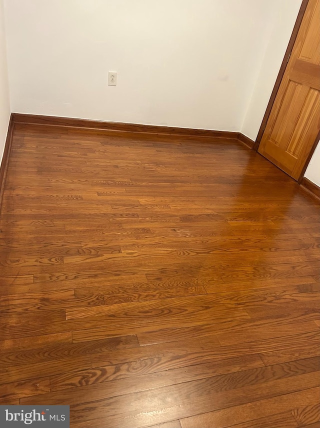 empty room featuring dark wood-type flooring and baseboards