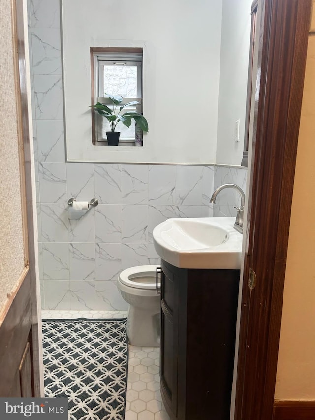bathroom featuring vanity, toilet, tile walls, and a wainscoted wall